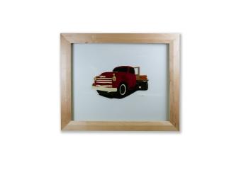 An image of a red truck made out of wood within a wood shadow box