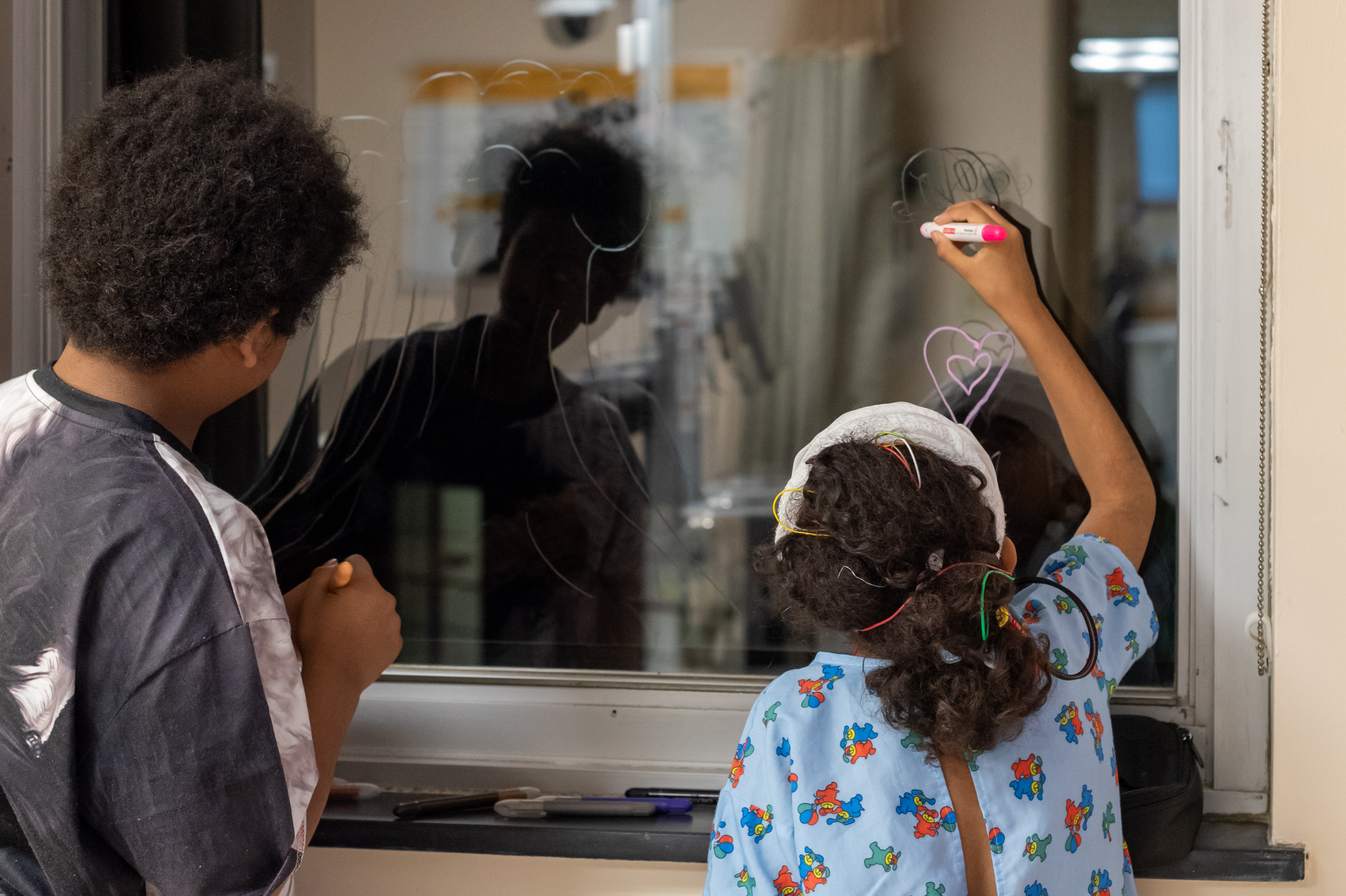 Art From the Heart participants drawing on a hospital window