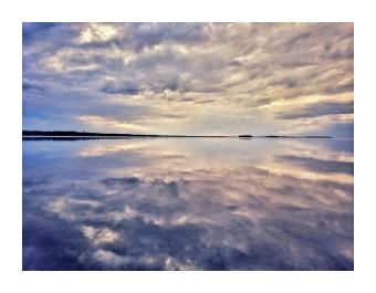 A photograph of a lake mirroring a cloud strewn sky