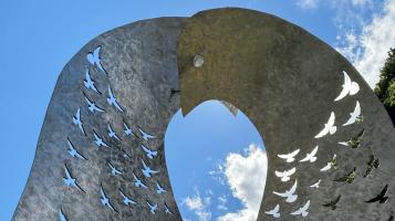 A close up of the top of a steel sculpture of two birds embracing.