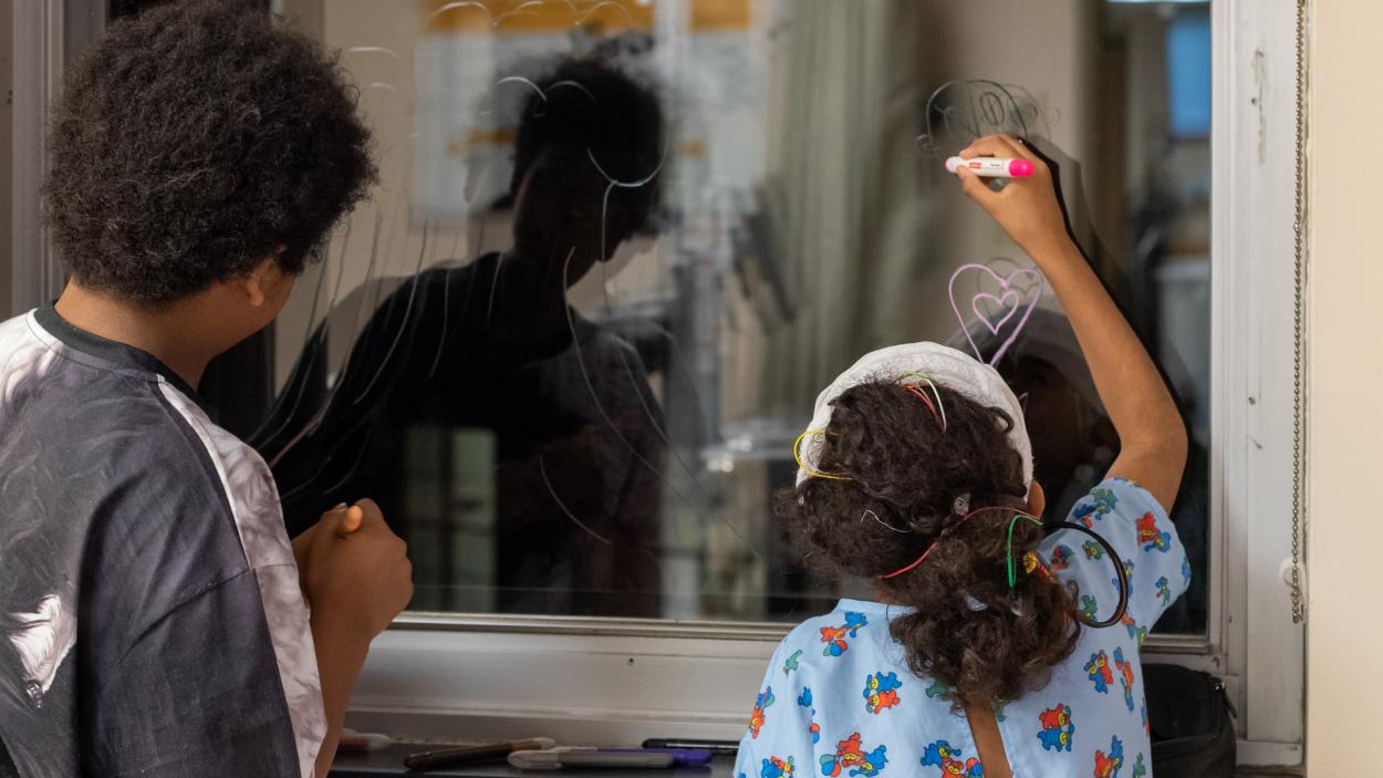 Art From the Heart participants drawing on a hospital window